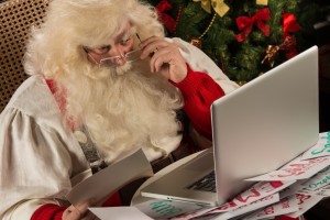 Santa checking his store for holiday online sopping season. 